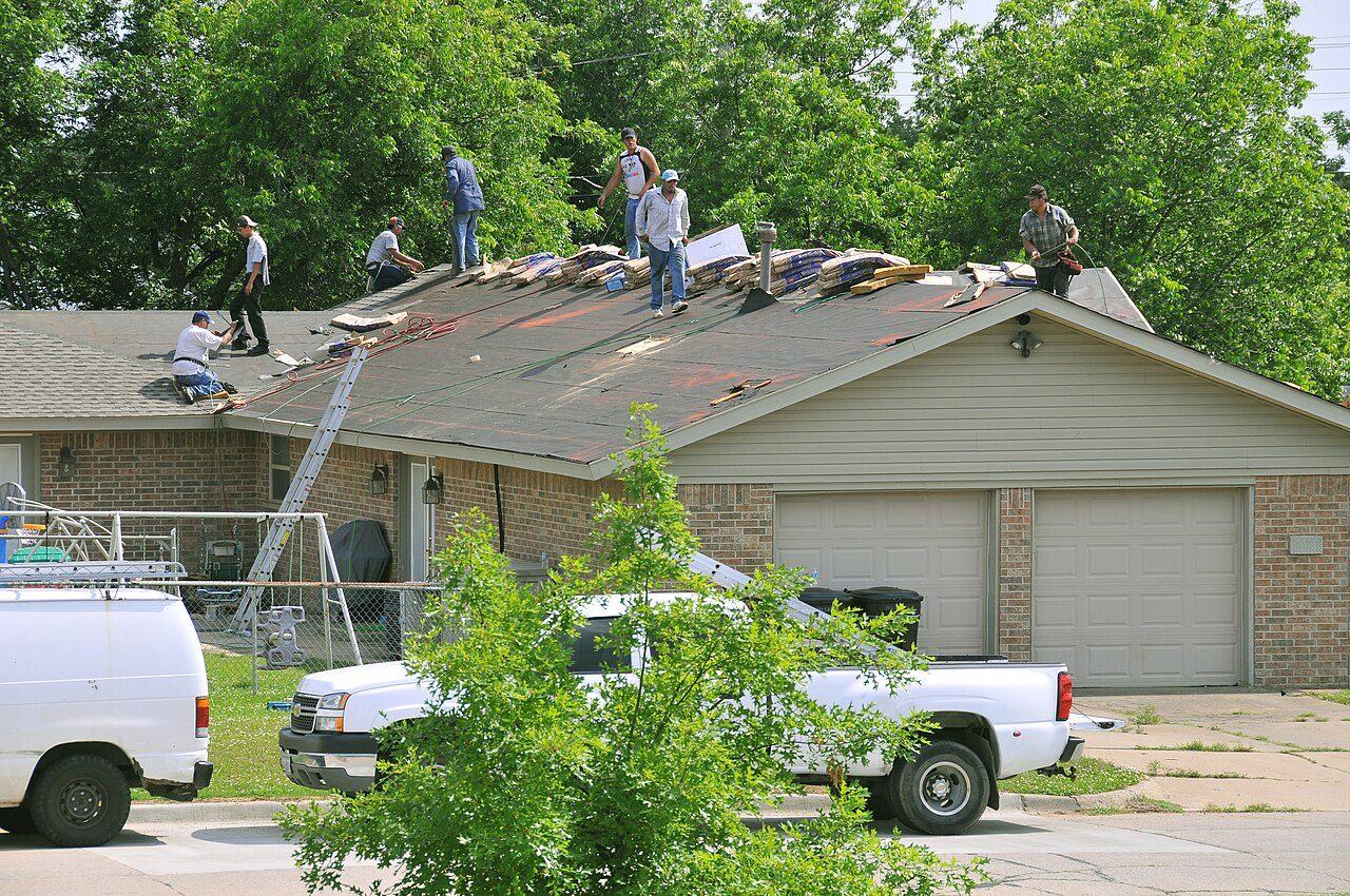 Photo of roof repair workers replacing damaged shingles